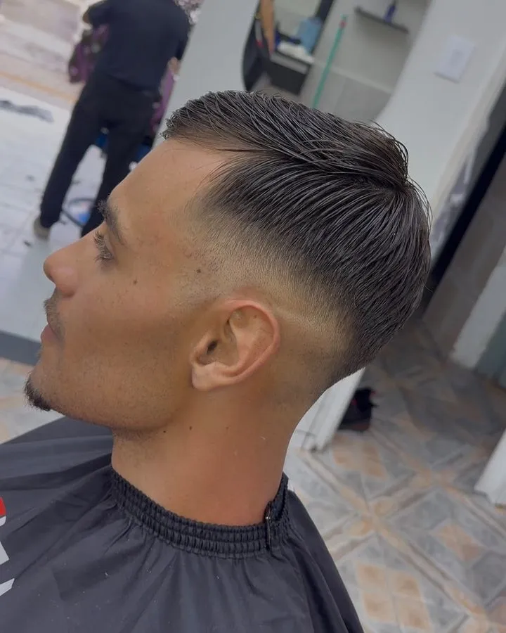 Degradê médio com topo penteado para trás, de perfil