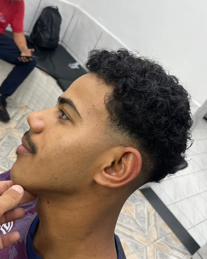 Degradê baixo com cachos no topo, de perfil