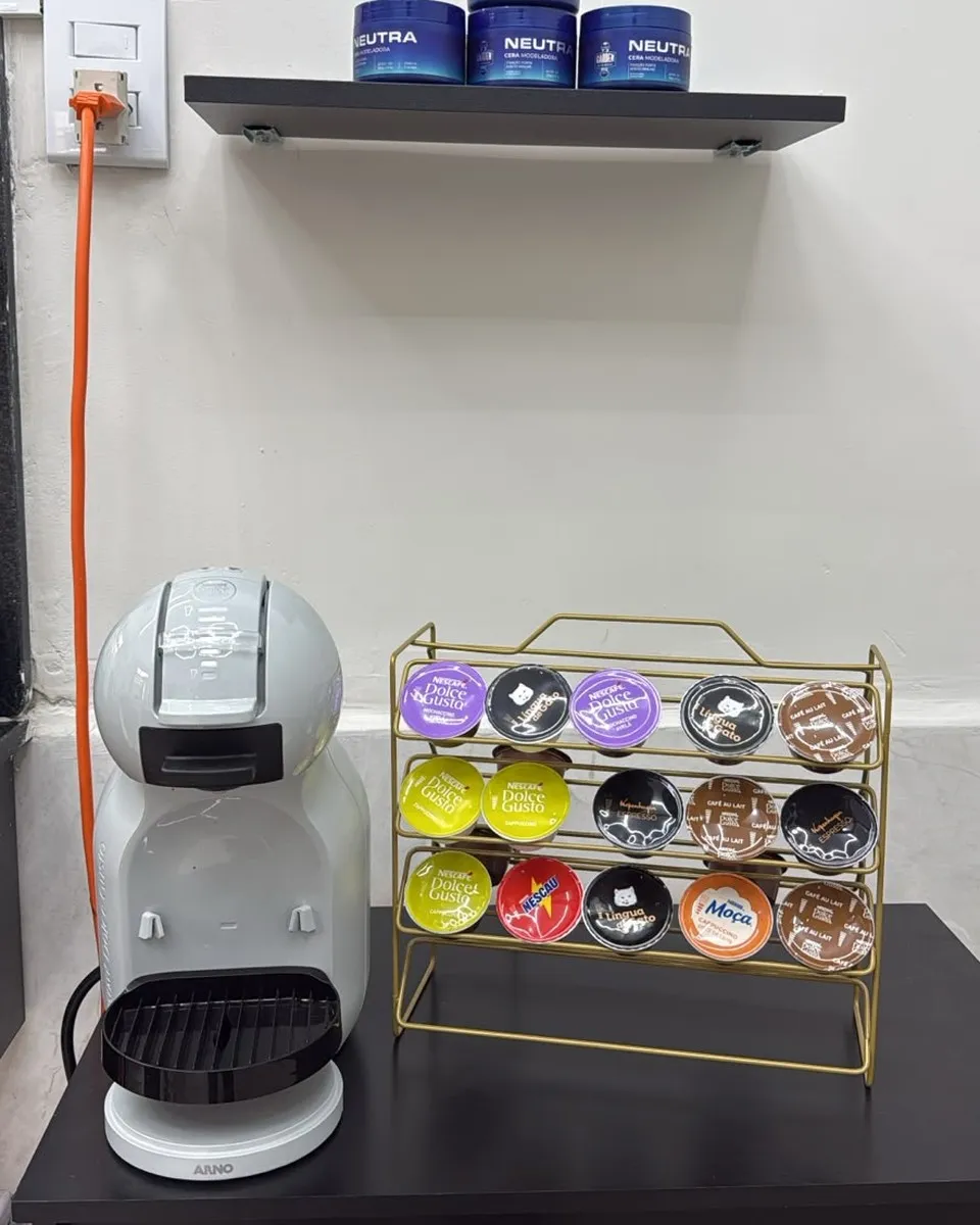 Cantinho da barbearia com máquina de café e pomadas